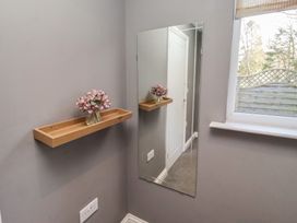 A hallway with a mirror and shelf containing flowers at Barn Owl in Otterburn