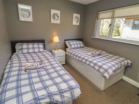 A bedroom with two single beds and a lamp at Barn Owl in Otterburn