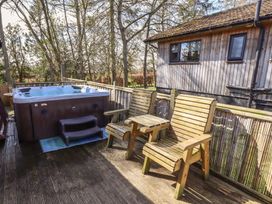 An outdoor area with a hot tub and wooden chairs at Barn Owl in Otterburn