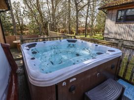 A hot tub on a deck surrounded by trees at Barn Owl in Otterburn