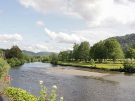 A river flowing through a landscape with trees on the banks and hills in the background at Ysgubor Newydd in Henryd near Conwy
