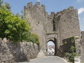 A road passing through an ancient stone castle gate with round towers and stone walls with greenery at Ysgubor Newydd in Henryd near Conwy