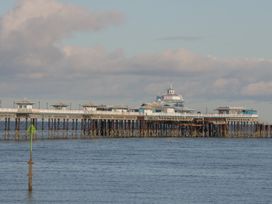 A pier extending over the sea with buildings on it under a cloudy sky