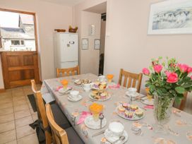 A dining room with a table set for tea with cakes and flowers at Ysgubor Newydd in Henryd near Conwy