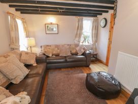 A living room with two brown leather sofas, a brown rug, a bean bag, a lamp, and curtains on windows at Ysgubor Newydd in Henryd near Conwy