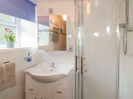 A bathroom with a sink vanity mirror shower and window with a blue blind at Ysgubor Newydd in Henryd near Conwy