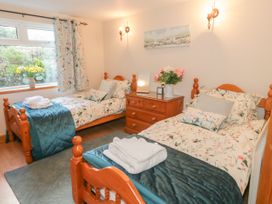 A bedroom with two single wooden beds floral bedding a wooden dresser flowers in a vase and a window at Ysgubor Newydd in Henryd near Conwy