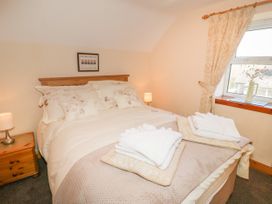 A bedroom with a double bed bedside tables and a window with curtains at Ysgubor Newydd in Henryd near Conwy
