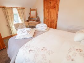 A bedroom with a bed and folded towels on it a wooden dresser with a mirror a chair and curtains at Ysgubor Newydd in Henryd near Conwy