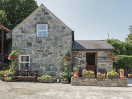 Stone cottage with flower pots and wooden benches outside at Ysgubor Newydd Henryd near Conwy