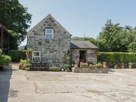 A stone cottage with flowers and potted plants outside at Ysgubor Newydd in Henryd near Conwy