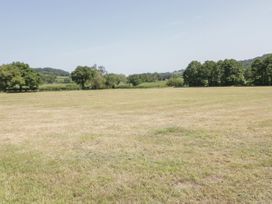 An open grassy field with trees in the background at Ysgubor Newydd in Henryd near Conwy
