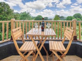 A wooden table with two wooden chairs on a balcony with a bottle of wine and two wine glasses at Barwood View in Torquay