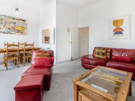 A living room with red leather sofas wooden dining table and glass top wooden coffee table at Barwood View in Torquay