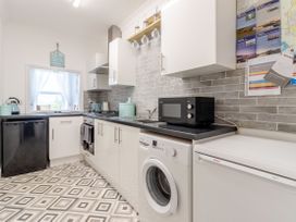 A kitchen with white cabinets black countertop and patterned floor at Barwood View in Torquay