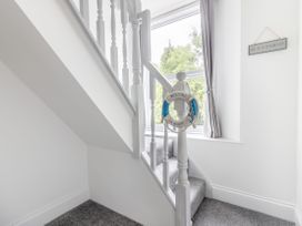 A staircase with white wooden banisters and grey carpet and a window with curtains in Barwood View Torquay