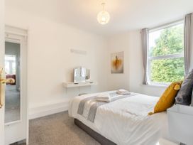 A bedroom with a bed, pillows, towels, a wall-mounted dressing table, a large window, and a door opening to another room at Barwood View in Torquay