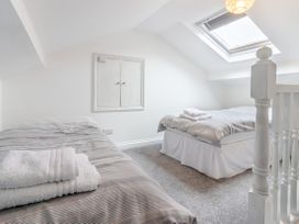 A bedroom with two single beds with towels on them a skylight window and a small cabinet on the wall at Barwood View in Torquay