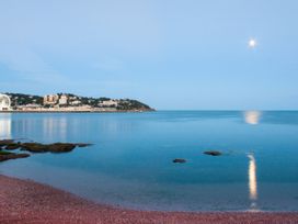 A coastal view with calm water rocks and buildings in the distance at Barwood View in Torquay
