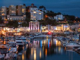 A marina with boats docked and buildings lit up at night at Barwood View in Torquay