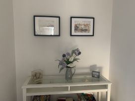 An entryway with photographs on the wall and a table with a vase and books at The Nest in Beadnell