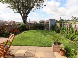 A garden with grass, plants, table, and shed at The Nest in Beadnell