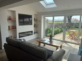 A living room with a television and a sliding door leading to the garden at The Nest in Beadnell