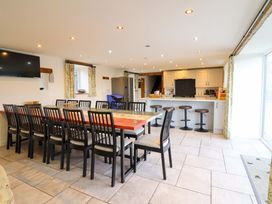 A kitchen with a large dining table and bar stools at Bwthyn Y Bugail (Shepherd's Cottage) Pedairffordd near Llanrhaeadr-Ym-Mochnant