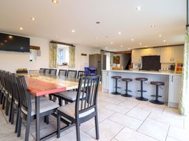 A kitchen with a large dining table and stools at Bwthyn Y Bugail (Shepherd's Cottage) Pedairffordd near Llanrhaeadr-Ym-Mochnant