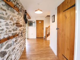 A hallway with a stone wall and wooden door at Bwthyn Y Bugail (Shepherd's Cottage) Pedairffordd near Llanrhaeadr-Ym-Mochnant