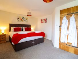 A bedroom featuring a bed with red accents, a side table, and decorative paintings at Bwthyn Y Bugail (Shepherd's Cottage) Pedairffordd near Llanrhaeadr-Ym-Mochnant