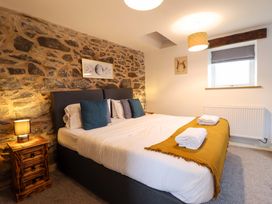A bedroom with stone wall and bed at Bwthyn Y Bugail (Shepherd's Cottage) Pedairffordd near Llanrhaeadr-Ym-Mochnant