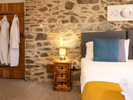 A bedroom with a bed and stone wall at Bwthyn Y Bugail (Shepherd's Cottage) Pedairffordd near Llanrhaeadr-Ym-Mochnant