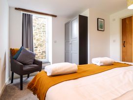 A bedroom with a bed, towels on top, and a chair at Bwthyn Y Bugail (Shepherd's Cottage) Pedairffordd near Llanrhaeadr-Ym-Mochnant