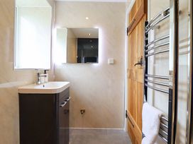 A bathroom with a sink, mirror, and door at Bwthyn Y Bugail (Shepherd's Cottage) Pedairffordd near Llanrhaeadr-Ym-Mochnant