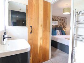 A bathroom with a sink and a wooden door leading to a bedroom at Bwthyn Y Bugail (Shepherd's Cottage) Pedairffordd near Llanrhaeadr-Ym-Mochnant