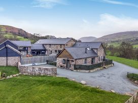 A stone house with a gravel driveway and green lawn at Bwthyn Y Bugail (Shepherd's Cottage) Pedairffordd near Llanrhaeadr-Ym-Mochnant