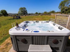 An outdoor hot tub with bubbling water a bottle of champagne and two glasses on the edge in a grassy field at The Wren in Llysfaen