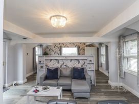 A living room with a sofa, table, and light fixture at The Wren in Llysfaen