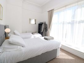 A bedroom with two beds, a lamp, and a clothes rack at Sunnymeade in Buxton, Norfolk