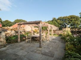 A garden with a table and chairs under a pergola at Bute Cottage in Lockton near Pickering