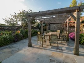 A garden with a wooden pergola and dining set at Bute Cottage in Lockton near Pickering