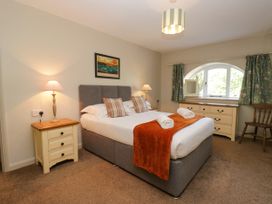 A bedroom with a bed, lamps, and dresser at Windermere at the Graythwaite Estate near Hawkshead