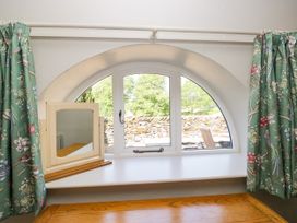 A window with green curtains and a mirror on a shelf at Windermere at the Graythwaite Estate near Hawkshead