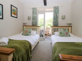 A bedroom with two beds and a door leading to an outdoor area at Windermere at the Graythwaite Estate near Hawkshead