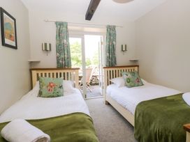 A bedroom with two single beds and a door leading outside at Windermere at the Graythwaite Estate near Hawkshead