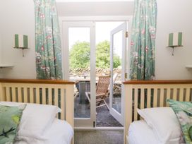 A bedroom with two beds and open doors leading to a patio area at Windermere at the Graythwaite Estate near Hawkshead