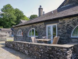 An outdoor area with a stone wall, table, and chairs at Windermere at the Graythwaite Estate near Hawkshead