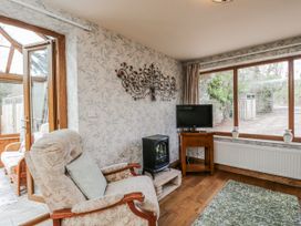 A snug with an armchair and television at Calcott Annexe in Whitchurch, Herefordshire