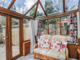 A conservatory with a sofa and large windows at Calcott Annexe in Whitchurch, Herefordshire